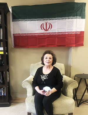 Woman seated in front of flag.