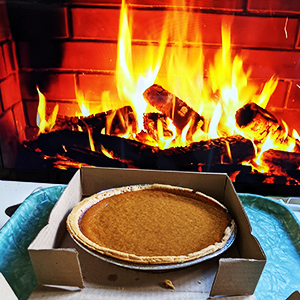 Pumpkin pie in front of a fireplace.